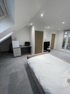 a white bedroom with a large bed and a desk at Studio Flat near wembley arena in Wealdstone