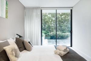 Schlafzimmer mit einem weißen Bett und einem großen Fenster in der Unterkunft LEAFY INNER CITY APARTMENT / CAMPERDOWN in Sydney