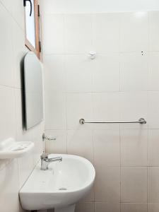 Baño blanco con lavabo y espejo en Cozy Hotel Dhermi en Dhërmi