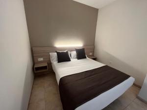 1 dormitorio con 1 cama grande con sábanas y almohadas blancas en Vas Málaga Ciudad, en Málaga