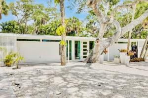 un garaje blanco con un árbol delante en Zachs Siesta Key Beach House Pet Friendly, en Siesta Key
