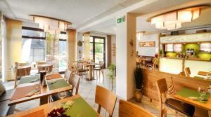 ein Restaurant mit Tischen und Stühlen in einem Zimmer in der Unterkunft Rennsteighotel Grüner Baum in Schmiedefeld am Rennsteig