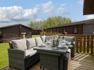 a patio with a couch and a table on a deck at Lakeland Dream South Lakeland Leisure Lodge in Carnforth