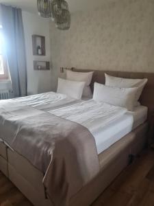 uma grande cama branca com lençóis e almofadas brancos em Apartment Bergliebe em Oberammergau