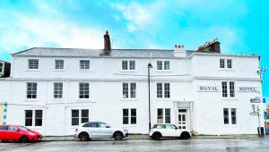 two cars parked in front of a white building at Royal Suites Kirkcudbright in Kirkcudbright