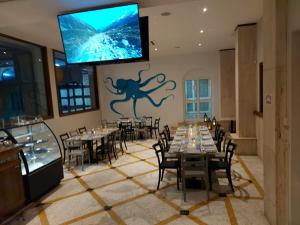 a dining room with tables and a tv on the wall at Ambassador Hotel in St Paul's Bay