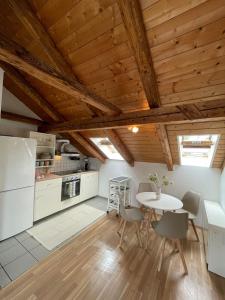 Il comprend une cuisine avec des plafonds en bois, une table et des chaises. dans l'établissement BullsLiving Seeapartment 6 Am Corso, à Velden am Wörther See
