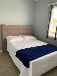 ein Schlafzimmer mit einem Bett mit einer blauen Decke darauf in der Unterkunft Apto 28A - Residencial Palladium Centro, Penha SC in Penha