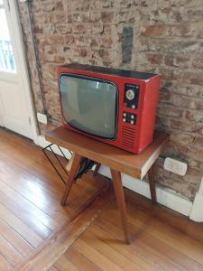 un viejo televisor rojo sentado en una mesa de madera en SANTELMO en Buenos Aires