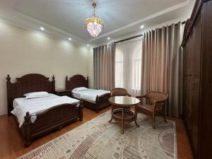 1 dormitorio con 2 camas, mesa y lámpara de araña en Hello Dushanbe Hostel, en Dushanbe