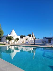 uma piscina com água azul em frente a um edifício em Trullo il Gelso em San Michele Salentino