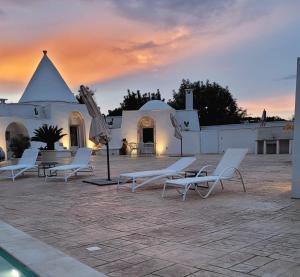 um grupo de cadeiras brancas sentadas em frente a um edifício em Trullo il Gelso em San Michele Salentino