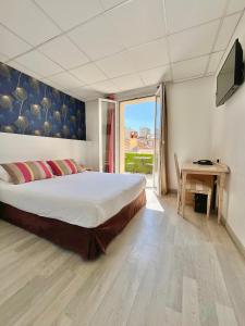 1 dormitorio con 1 cama, TV y mesa en Hôtel de Flore en Saint-Raphaël