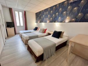 una habitación de hotel con 2 camas y un cuadro en la pared en Hôtel de Flore, en Saint-Raphaël