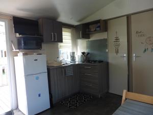 a small kitchen with a white refrigerator and a table at Mobil home Saint Georges de Didonne in Saint-Georges-de-Didonne