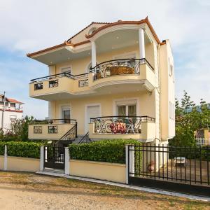 a white house with balconies and a fence at Prime Luxury Villa beach front in Nea Vrasna