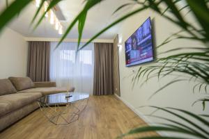 een woonkamer met een bank en een tv aan de muur bij Hermann Central Apartment in Sibiu