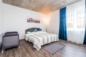 um quarto com uma cama com um cobertor listrado e cortinas azuis em Perla Hradce 402 em Hradec Králové