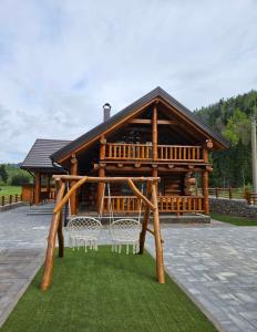 a large wooden cabin with two white chairs in front of it at Villa Korina in Fužine