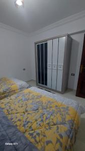 um quarto com uma cama com um cobertor amarelo e azul em Eamar tower 2 em Tanta