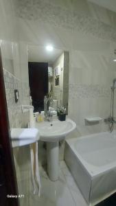 een badkamer met een wastafel, een bad, een wastafel en een spiegel bij Eamar tower 2 in Tanta