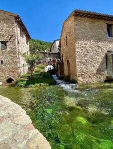 un fiume di fronte a due edifici in pietra di affittacamere Folignocentro a Foligno