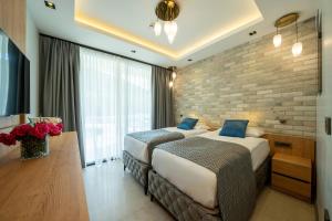 2 bedden in een hotelkamer met een bakstenen muur bij Batıhan Vadi Hotel in Kuşadası