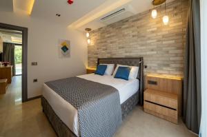een slaapkamer met een bed en een bakstenen muur bij Batıhan Vadi Hotel in Kuşadası