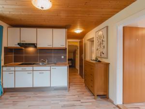 フッシュ・アン・デア・グロックナーシュトラーセにあるHoliday Home Bergfried - FUC150 by Interhomeの白いキャビネットと木製の天井が備わるキッチン