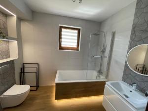 a bathroom with a tub and a toilet and a sink at Apartament Rybical in Ryn