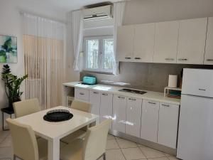 a white kitchen with a table and a white refrigerator at Holiday Home Katarina - SRD330 by Interhome in Rovanjska