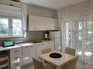 a kitchen with white cabinets and a table with chairs at Holiday Home Katarina - SRD330 by Interhome in Rovanjska