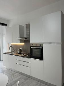 uma cozinha com armários brancos e um forno com placa de fogão em Nonna Gina House em Tortolì