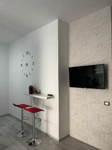 um quarto com dois bancos vermelhos e um relógio na parede em Nonna Gina House em Tortolì
