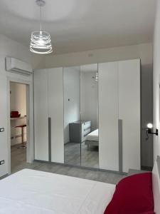 um quarto com paredes brancas e uma cama e um espelho em Nonna Gina House em Tortolì