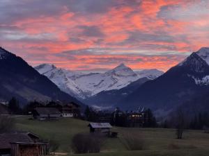 a sunset over a mountain range with houses and mountains at Apartment Aerneli- Chalet by Interhome in Gstaad