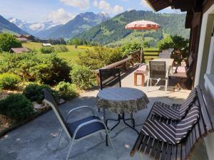 a table and chairs on a patio with mountains in the background at Apartment Aerneli- Chalet by Interhome in Gstaad