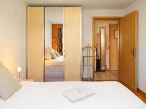 Schlafzimmer mit einem weißen Bett und einem Spiegel in der Unterkunft Apartment Belmi by Interhome in Zweisimmen