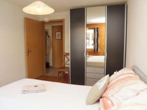 a bedroom with a white bed and a mirror at Apartment Belmi by Interhome in Zweisimmen +26 photos