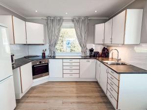 a kitchen with white cabinets and a sink and a window at Holiday Home Tantestova - FJS296 by Interhome in Balestrand