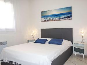 ein Schlafzimmer mit einem großen weißen Bett mit blauen Kissen in der Unterkunft Apartment Beau Rivage by Interhome in Carqueiranne