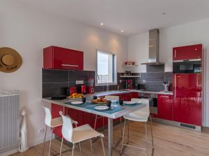 eine Küche mit roten Schränken und einem Tisch mit Stühlen in der Unterkunft Holiday Home Ty Amiets - CED245 by Interhome in Cléder
