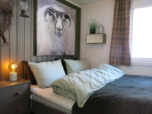ein Schlafzimmer mit einem Bett und einem Bild einer Ziege in der Unterkunft Chalet Knøttebu - SOW054 by Interhome in Øyuvstad