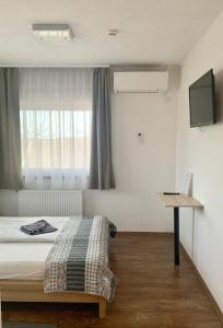 1 dormitorio con cama y escritorio con ordenador portátil en Toscan Panzió en Gyál