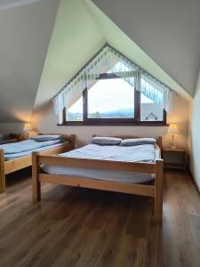 2 Betten in einem Zimmer mit Fenster in der Unterkunft Willa Natia in Kluszkowce