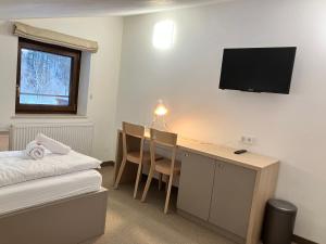 Pokój hotelowy z biurkiem i telewizorem na ścianie w obiekcie Stubnerhof w mieście Bad Gastein