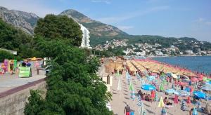 a beach with chairs and umbrellas and a waterfall at Hostel Marina in Sutomore
