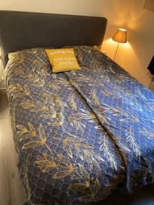 Una cama con un edredón azul con una etiqueta amarilla. en Chalet Wild Forest, knus chalet op de Veluwe met gratis parkeren en Putten