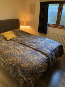 a bed with a blue comforter in a bedroom at Chalet Wild Forest, knus chalet op de Veluwe met gratis parkeren in Putten