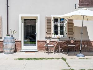 een patio met een tafel en stoelen en een parasol bij Apartment Cascina MonteRosa-1 by Interhome in Costigliole dʼAsti